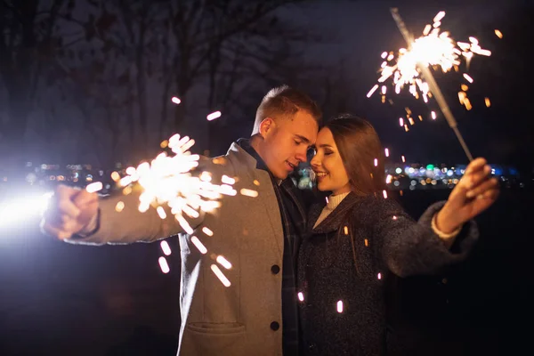 Homem e mulher segurando um sparkler ardente. Fogo de bengala — Fotografia de Stock