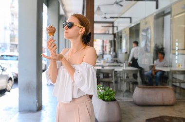 Açık closeup moda portre genç hipster çılgın kız sıcak havalarda yuvarlak ayna güneş gözlüğü var eğlenceli ve iyi bir ruh hali yaz aylarında dondurma yeme