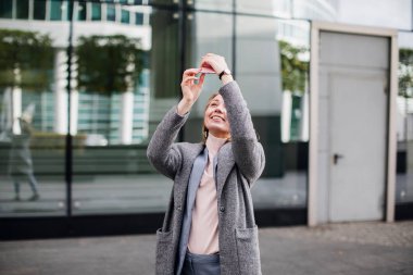 Güzel genç bir kadın akıllı telefonuyla selfie çekiyor.