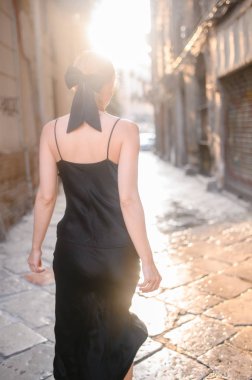 Siyah elbiseli genç kız Avrupa sokaklarında yürüyor