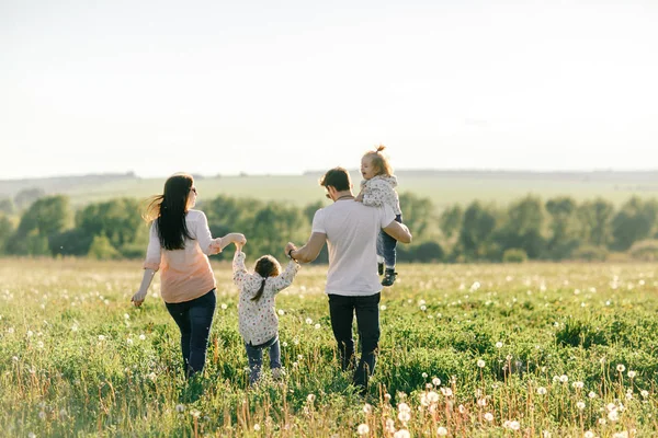 Mutlu genç aile dışarıda yeşil doğada birlikte vakit geçiriyor.