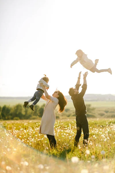 Gelukkige familie wandelingen in de natuur. Mam en pap gooien hun kinderen — Stockfoto