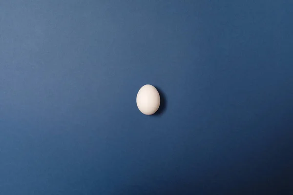 蓝色背景上的单个白色蛋。 假期的概念。 复活节快乐 — 图库照片