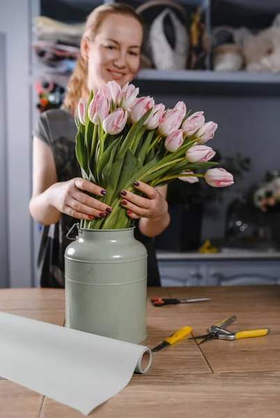 Florist girl makes a bouquet of tulips in a flower shop