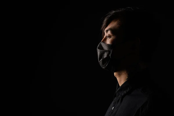 Koronavirüsü korumak için tıbbi maskeli bir Asyalı. Kirli havası olan genç bir Asyalı şehirde yaşıyor.