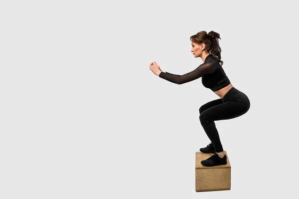 Entrenamiento de mujer deportiva, bombeando músculos de manos y piernas. Foto de mujer en ropa deportiva negra. Fuerza y motivación. Vista lateral — Foto de Stock