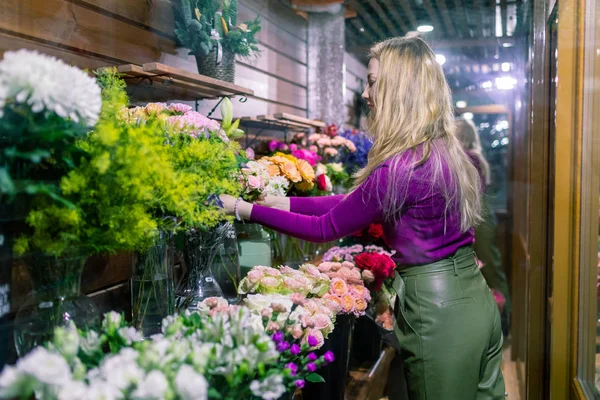 Jovem florista de pé e trabalhando na loja de flores — Fotografia de Stock