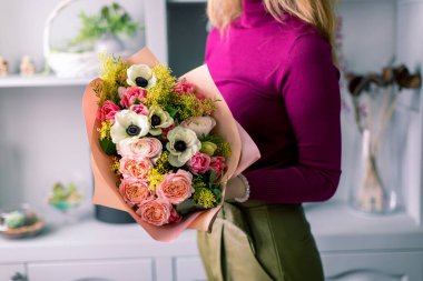 Çiçekçi bir buket tutuyor. Güzel bahar çiçekleri. Karışımı çiçekler ile düzenleme. Bir çiçek dükkanı kavramı, küçük bir aile iş. İş çiçekçi. Kopyalama alanı