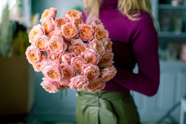 Kadının elinde kocaman, güzel bir buket karışık çiçek. Çiçek dükkanı konsepti. Güzel, taze bir buket. Çiçek teslimatı.