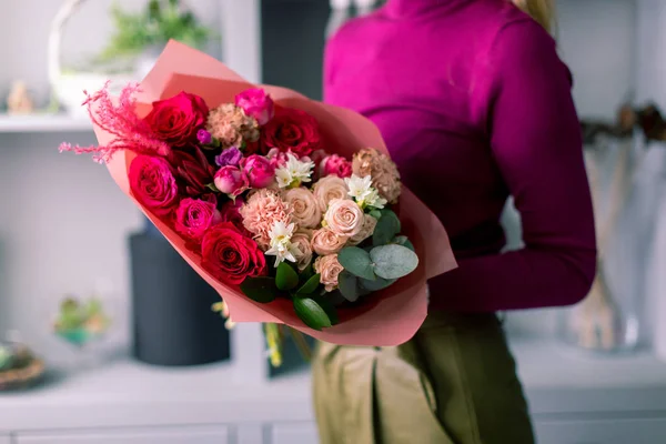 Tonos rojos Hermoso ramo de flores mixtas en manos de mujeres. el trabajo de la floristería en una florería. Bonito ramo fresco. Entrega de flores. —  Fotos de Stock