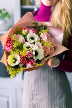 Yakın çekim elinde çiçekler. Çiçekçi işyeri. Kadın bir buket gül, kasımpatı, karanfil ve diğer çiçekleri ile düzenlenmesi. Floristik ana sınıfları veya dersleri öğretmeni