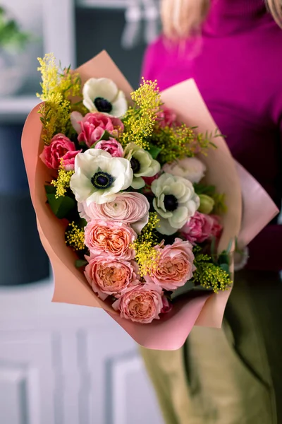 Квіти в руці. Флористське робоче місце. Жінка влаштовує букет з трояндами, хризантемою, гвоздикою та іншими квітами. Викладач флористики на майстер-класах або курсах — стокове фото