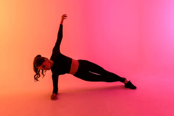 Chica deportiva sobre un fondo de color brillante hace ejercicios . — Foto de Stock