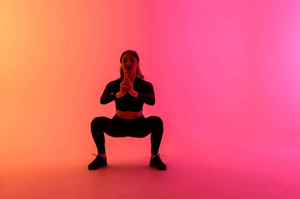 Chica deportiva sobre un fondo de color brillante hace ejercicios . — Foto de Stock