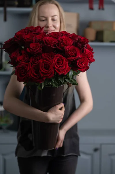 Chica sosteniendo un enorme ramo de rosas rojas en sus manos —  Fotos de Stock