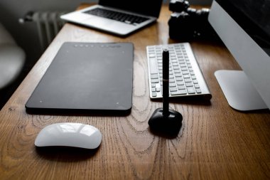 Fotoğrafçı, dijital tablet ve stilus kalem kullanarak dizüstü bilgisayarda resim çiziyor ve rötuşluyor. Evdeki çalışma alanı 