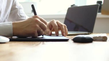 Fotoğrafçı, dijital tablet ve stilus kalem kullanarak dizüstü bilgisayarda resim çiziyor ve rötuşluyor. Evdeki çalışma alanı 