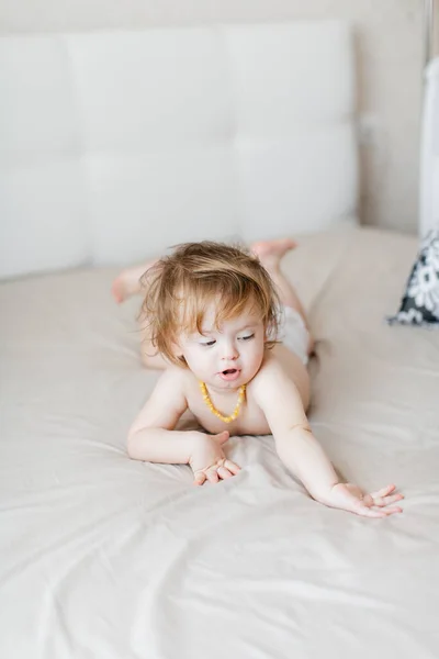 Małe dziecko w pieluszce leży na łóżku i śmieje się — Zdjęcie stockowe