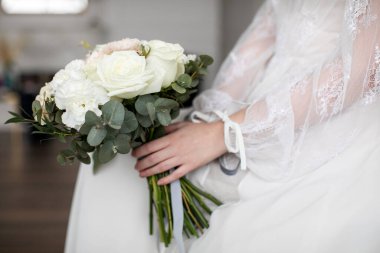 Gelin elinde pastel çiçeklerden bir buket, klasik tarzda, bulanık bir arka plan.