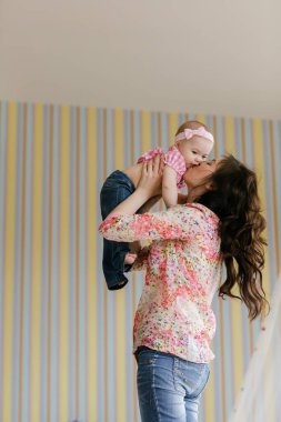 Sevgi dolu, genç bir anne gülüyor, gülümsüyor, komik bir kız çocuğu evde eğleniyor.