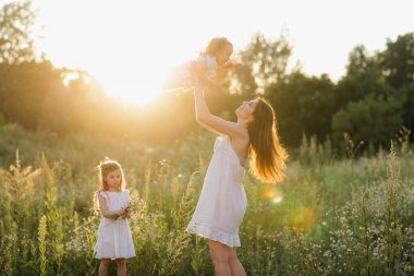 Mutlu aile kızı tatilde annesine sarılıyor. Aile doğada yürür..