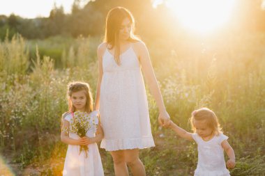 Mutlu aile kızı tatilde annesine sarılıyor. Aile doğada yürür..