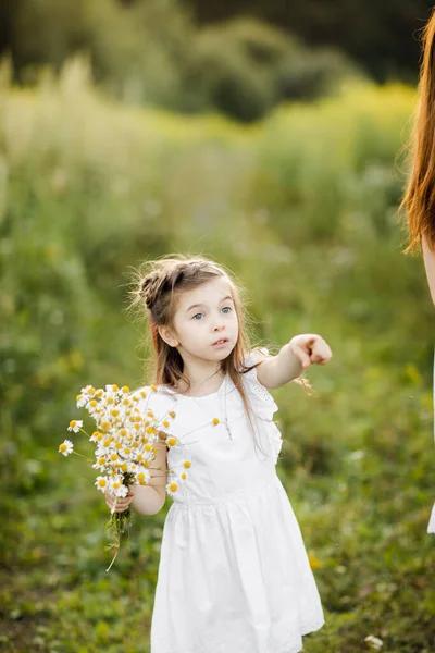 Portrét roztomilé holčičky s květinami. Dívka v zahradě s kyticí heřmánku — Stock fotografie