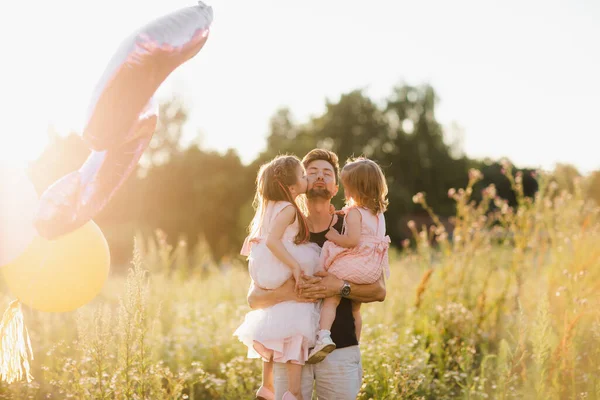 Щаслива сім'я і батьки день. Дві доньки цілуються і обіймають тата на відкритому повітрі — стокове фото