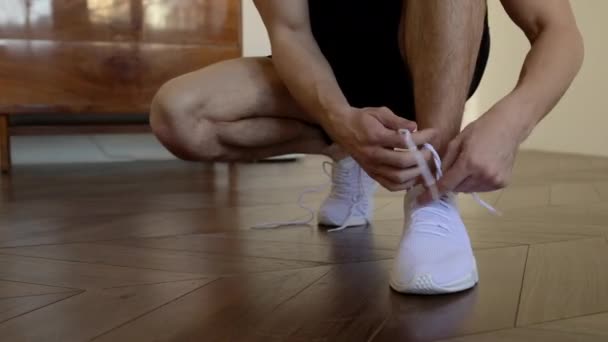 Primer plano de un hombre mayor deportivo atando cordones en una zapatilla de deporte. Entrenamiento en casa . — Vídeos de Stock