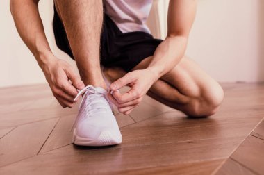 Spor ayakkabı bağcıklarını spor ayakkabısına bağlayan son sınıf öğrencisine yakın çekim. Ev çalışması.