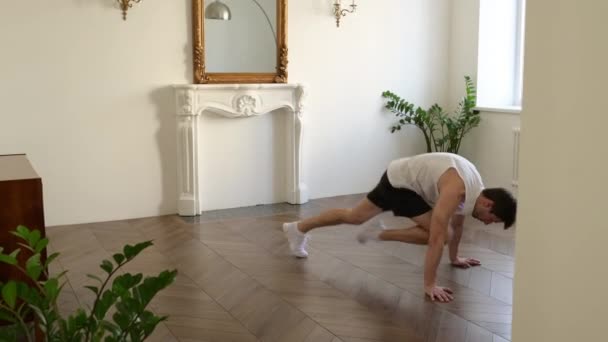 Zijaanzicht van knappe jonge sporter die thuis cardio-oefeningen doet op plank positie — Stockvideo