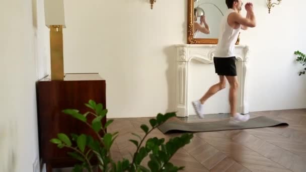 Bonito cara está se exercitando em casa fazendo exercícios esportivos para pernas e corpo. Conceito de homens, casa e bem-estar . — Vídeo de Stock