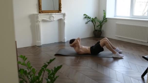 Rester à la maison pendant la quarantaine. Jeune homme faisant de l'exercice, faire des craquements torsion sur le tapis à la maison — Video