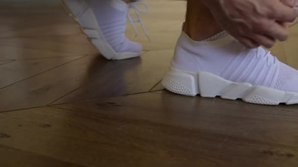 Крупним планом спортивний старший чоловік зав'язує шнурки на кросівки. Домашнє тренування . — стокове відео