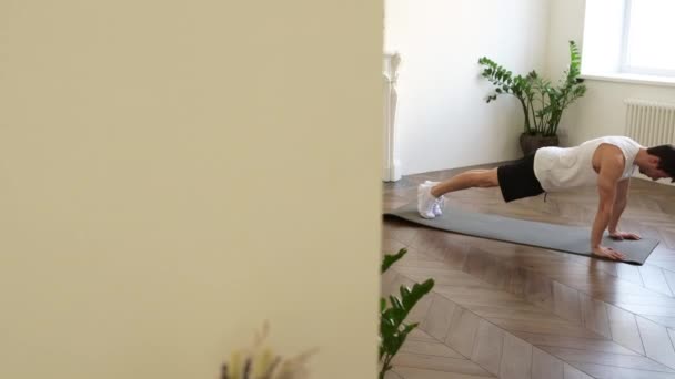 Hombre sano hace un gran esfuerzo para completar flexiones en la sala de estar de su casa — Vídeo de stock