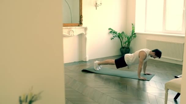 Hombre sano hace un gran esfuerzo para completar flexiones en la sala de estar de su casa — Vídeo de stock