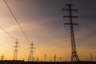 Gün batımında yüksek voltajlı elektrik hatları. Elektrik dağıtım istasyonu