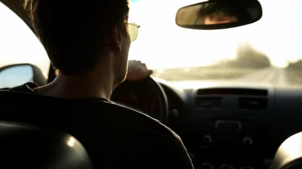 Una vista trasera cercana de un hombre adulto con gafas de sol conduciendo un coche durante el día. Brillante sol brilla en sus ojos — Vídeos de Stock