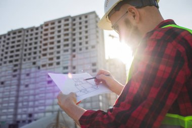 İnşaat alanındaki Mühendislik Danışmanlığı elinde planları tutuyor. İnşaat müfettişi