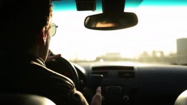 Güneş gözlüklü yetişkin bir adamın gündüz vakti araba sürüşünü yakından izlemek. Parlak güneş gözlerinde parlıyor.