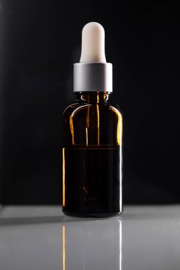 Siyah zemin üzerinde doğal organik yağ izole edilmiş. Kahverengi şişede vücut yağı