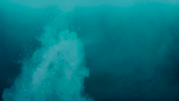 Stock video Színes festékcseppek keverednek a vízben lassított felvételben. Sima tinta örvénylő és fröccsenő felülről víz alatti. — Stock videók