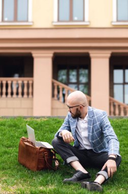 Sokakta dizüstü bilgisayar kullanan şık bir adam. Serbest çalışma kavramı