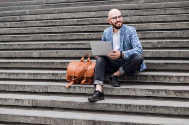Sokakta dizüstü bilgisayar kullanan şık bir adam. Serbest çalışma kavramı
