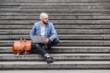 Sokakta dizüstü bilgisayar kullanan şık bir adam. Serbest çalışma kavramı