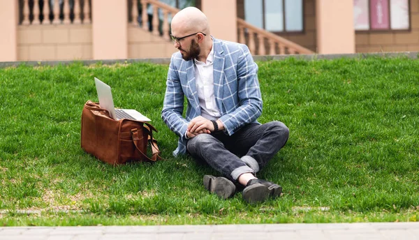 Стильный человек, использующий ноутбук на улице. Концепция внештатной работы — стоковое фото