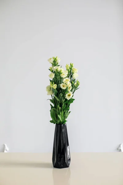 Bokros rózsák fekete vázában fehér háttérrel. Egy csokor rózsa egy üvegvázában.. — Stock Fotó