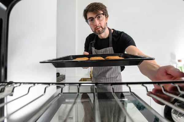 Male cook baking cookies in the oven. inside view of the oven