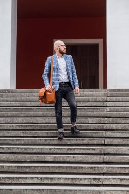  Mavi kareli ceketli şık genç adam merdivenlerden iniyor.