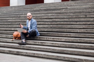  Dizüstü bilgisayarı olan iş adamı merdivenlerde çalışıyor.